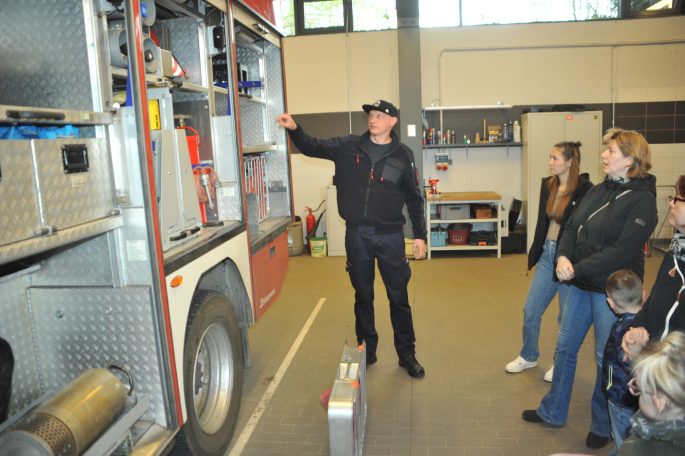 Ein Feuerwehrmann zeigt Ausrüstung in der Feuerwache einer Gruppe von Menschen.